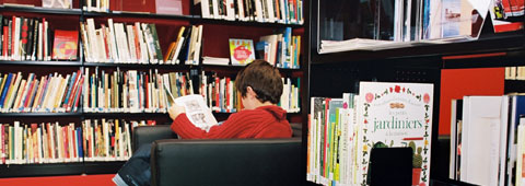 Un enfant lisant un livre dans une bibliothèque Un enfant lisant un livre dans une bibliothèque