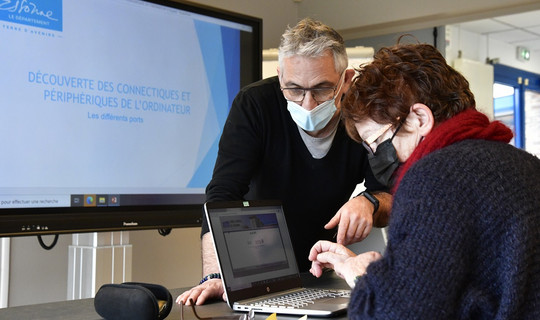 Un conseiller numérique apprend à une participante à utiliser un ordinateur