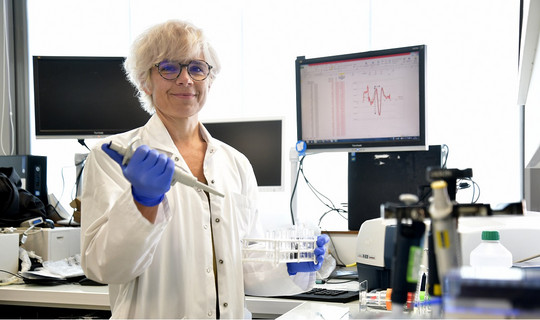 Un femme souriante travaille dans son laboratoire de recherche scientifique