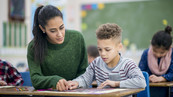 Une femme aide un petit garçon durant la classe