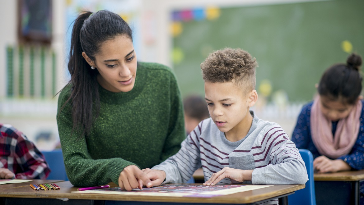 Une femme aide un petit garçon durant la classe