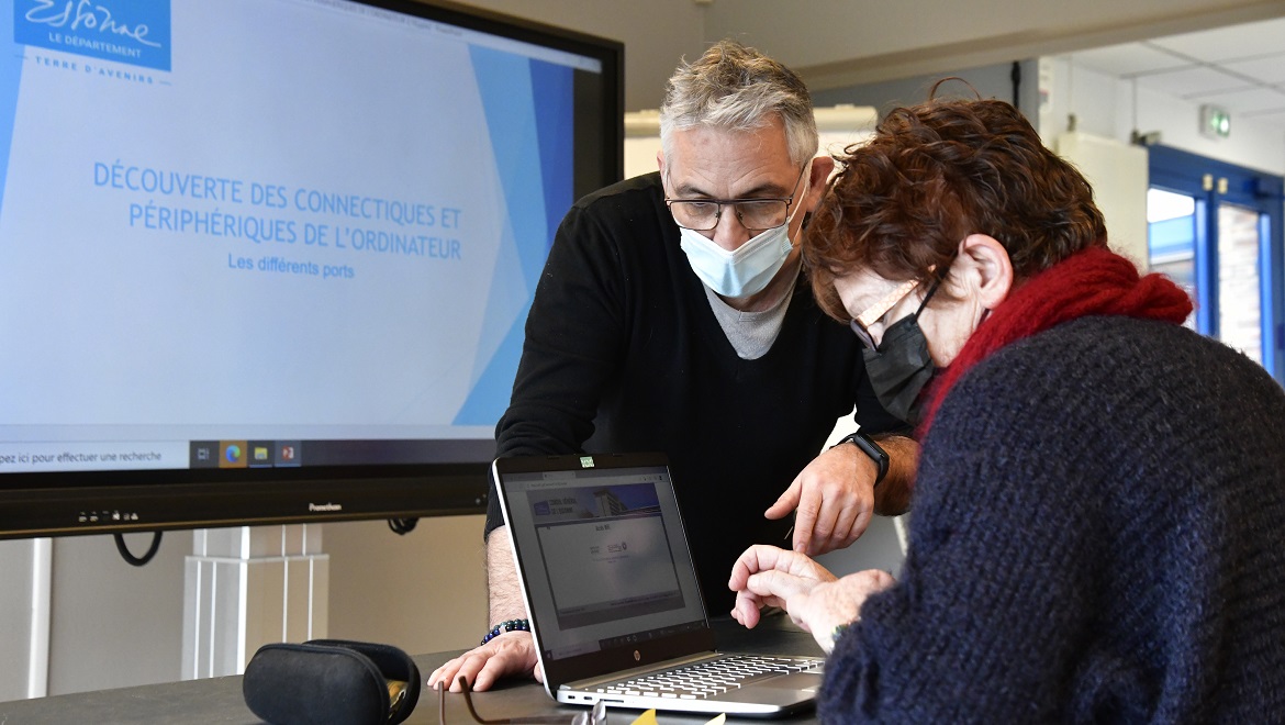 Un conseiller numérique apprend à une participante à utiliser un ordinateur