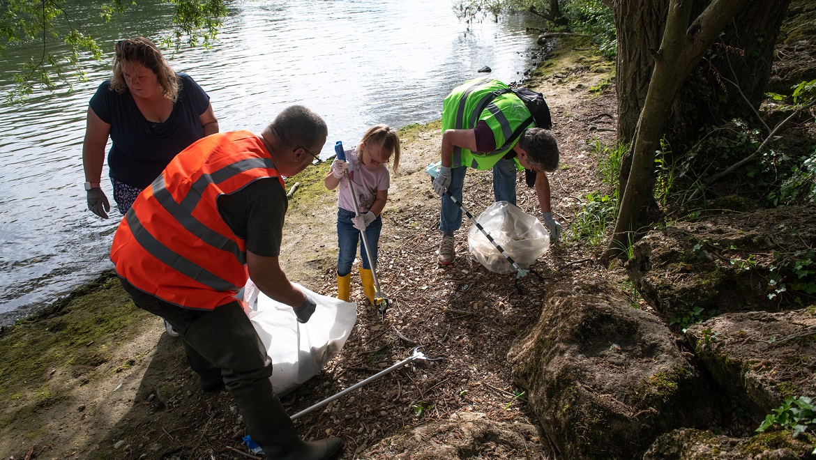 Une famille de volontaires ramasse les déchets devant une étendue d'eau